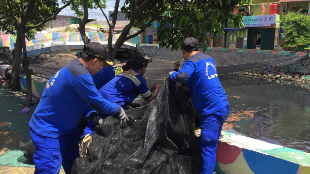 Petugas Sumber Daya Air (SDA) Jakarta menggulung jaring kali Item. (Foto: Fachrul Irwinsyah/kumparan)