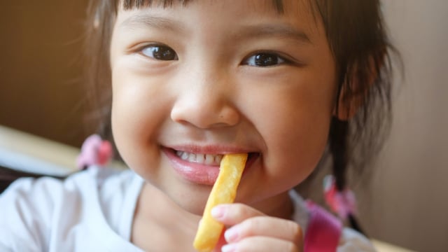 Ilustrasi anak makan kentang goreng (Foto: Shutterstock)