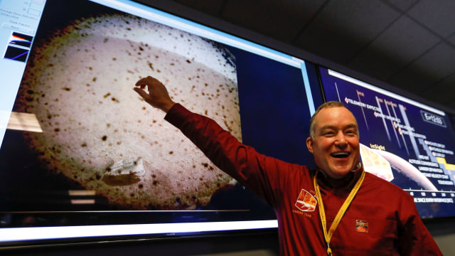 Project manager Tom HoffMan menunjukkan gambar pertama daratan Mars yang diambil oleh robot InSight NASA. (Foto: Al Seib/Pool via Reuters)