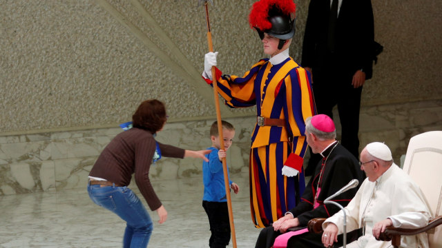 Seorang anak dicegah ibunya saat mengganggu ceramah Paus Fransiskus di ruang Paulus VI di Vatikan. (Foto: REUTERS/Max Rossi)
