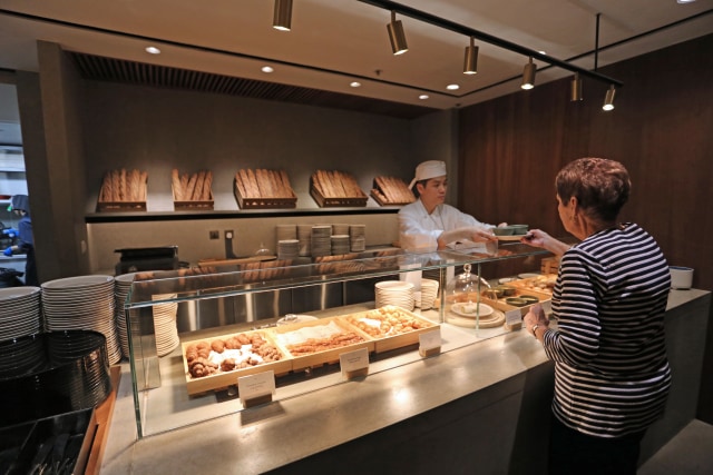 Salah seorang penumpang sedang mengambil pesanan makanan di Pier Business Lounge Cathay Pacific, Hong Kong International Airport. (Foto: Aria Sankhyaadi/kumparan)