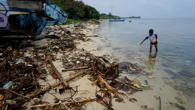 Seorang anak bermain di tepi Pantai Pulau Pari yang dipenuhi sampah. (Foto: Iqbal Firdaus/kumparan)