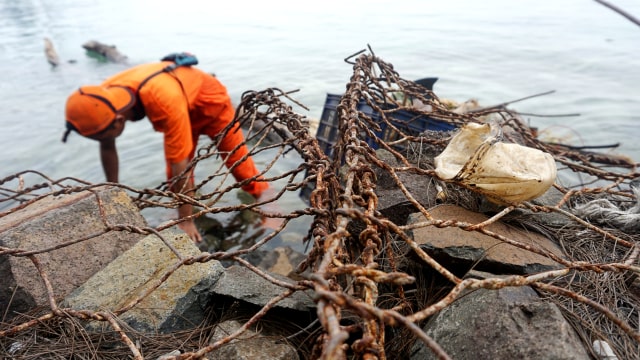 Petugas kebersihan membersihkan sampah di pinggir pantai Pulau Pari. (Foto: Iqbal Firdaus/kumparan)