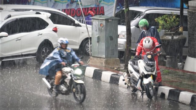 Pengendara motor yang berhenti untuk menggunakan mantel hujan di Jalan Gatot Subroto. (Foto: Iqbal Firdaus/kumparan)