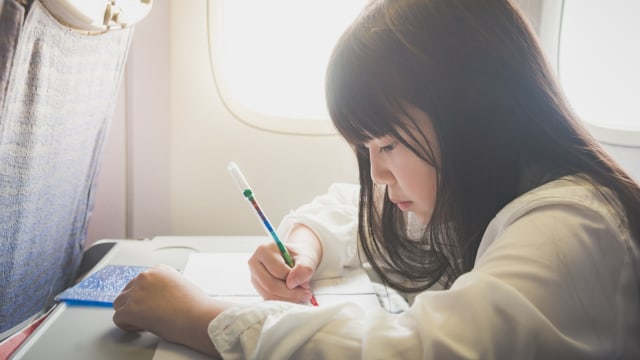 Anak mewarnai dalam pesawat. (Foto: Shutterstock)