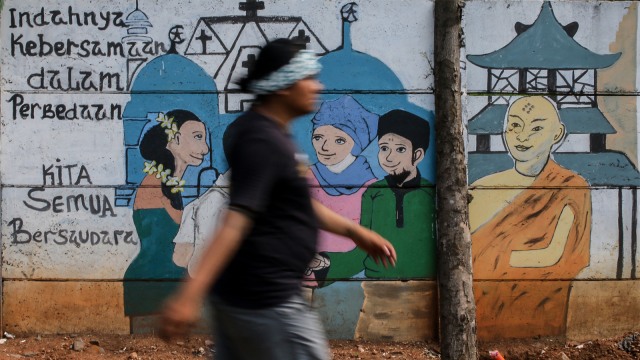 Warga melintas di depan mural bertema keberagaman umat beragama. (Foto:  ANTARA FOTO/Rivan Awal Lingga)
