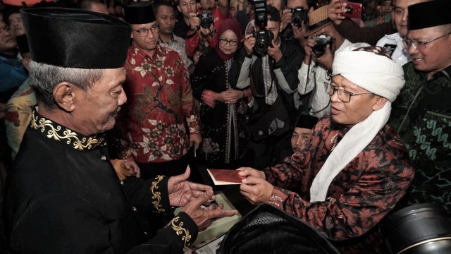 Gubernur DKI Jakarta Anies Baswedan dan AA Gym menyerahkan buku nikah pada pasangan tertua di nikah massal. (Foto: Jamal Ramadhan/kumparan)