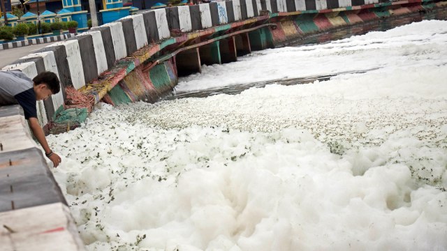Warga melihat kumpulan busa yang memenuhi Kali Item di Kawasan Kemayoran, Jakarta, Selasa (1/1/2019). (Foto: Antara/Galih Pradipta)