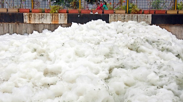 Warga melihat kumpulan busa yang memenuhi Kali Item di Kawasan Kemayoran, Jakarta, Selasa (1/1/2019). (Foto: Antara/Galih Pradipta)