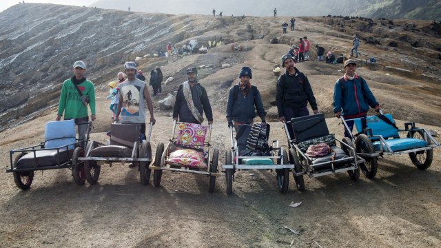 Sejumlah penambang belerang berfoto bersama dengan taksi atau troli saat menunggu pendaki yang akan menggunakan jasa mereka di puncak gunung Ijen. (Foto: Antara/M Agung Rajasa)