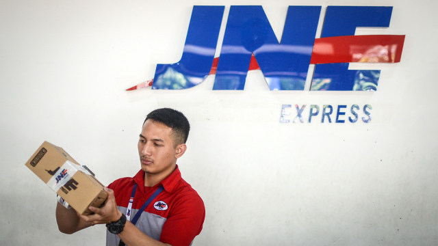 Pekerja membungkus paket di Kantor JNE. (Foto: ANTARA FOTO/Raisan Al Farisi)