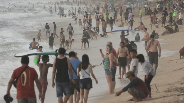 Wisatawan menikmati suasana Pantai Kuta, Badung, Bali, Senin (31/12/2018). (Foto: ANTARA FOTO/Fikri Yusuf)