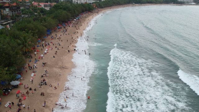 Wisatawan menikmati suasana Pantai Kuta, Badung, Bali, Senin (31/12/2018). (Foto: ANTARA FOTO/Fikri Yusuf)
