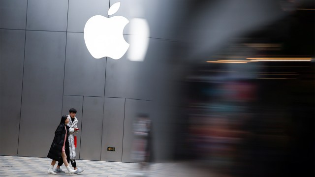 Sejumlah orang menggunakan smartphone di luar toko Apple.