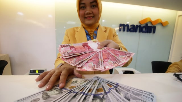 Teller Bank Mandiri menunjukkan uang pecahan Dolar AS dan Rupiah di Bank Mandiri KCP Jakarta DPR, Senin (7/1/2019). Kurs Rupiah terhadap Dolar AS menguat 1,3 persen menjadi Rp14.080.  Foto: ANTARA FOTO/Rivan Awal Lingga