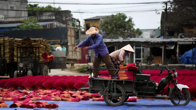 Para pekerja sedang mempersiapkan untuk proses pengeringan batang bambu yang telah diwarnai dan diberikan aroma dupa, Desa Quang Phu Cau, Hanoi, Vietnam. (Foto: AFP/Manan VATSYAYANA)