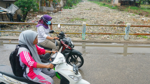 Pengendara sepeda motor yang melintas di atas jembatan Kali Pisang Batu, Bekasi. (Foto: Iqbal Firdaus/kumparan)