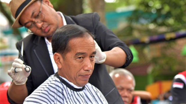 Presiden Joko Widodo saat dipangkas rambutnya oleh Herman, pemuda asal Garut. (Foto: Presidential Palace/Agus Suparto)