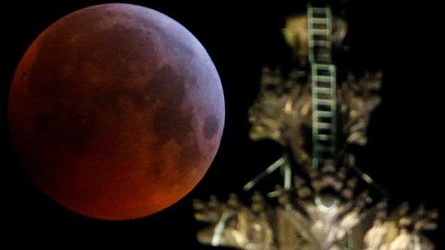 Fenomena 'super blood wolf moon' terlihat belakang katedral gothic selama gerhana bulan  di Cologne, Jerman, (21/1). (Foto: REUTERS / Thilo Schmuelgen)