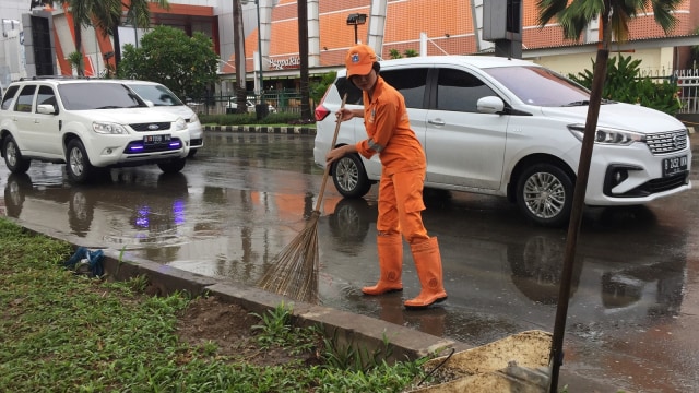 Sellha Purba, pekerja PPSU sedang bertugas menyapu jalanan yang tergenang air.  (Foto: Fachrul Irwinsyah/kumparan)