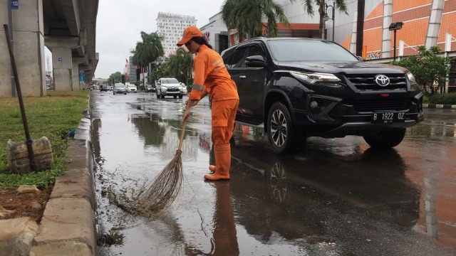 Sellha Purba, pekerja PPSU sedang bertugas menyapu jalanan yang tergenang air. Foto: Fachrul Irwinsyah/kumparan