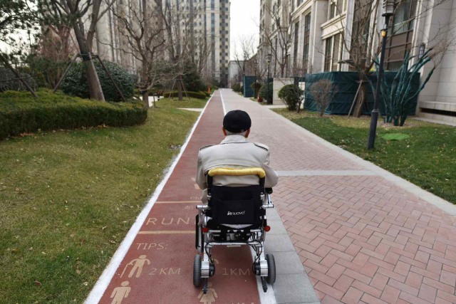 Saat seorang warga telah lanjut usia berjalan menuju apartemennya di komunitas Yanyuan, Beijing, China. (Foto: AFP/GREG BAKER )