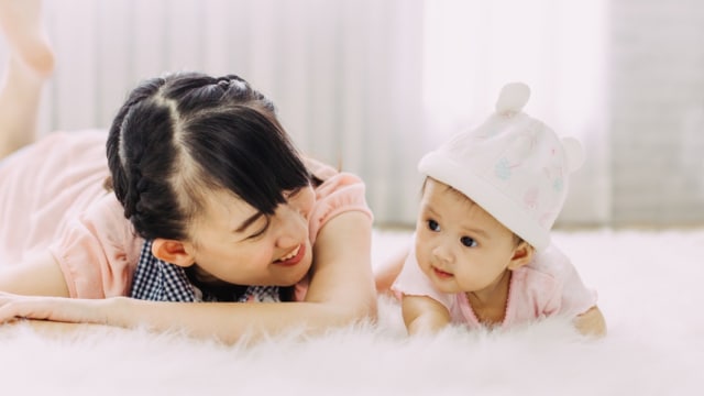 Ibu menemani bayi saat melakukan tummy time Foto: Shutterstock