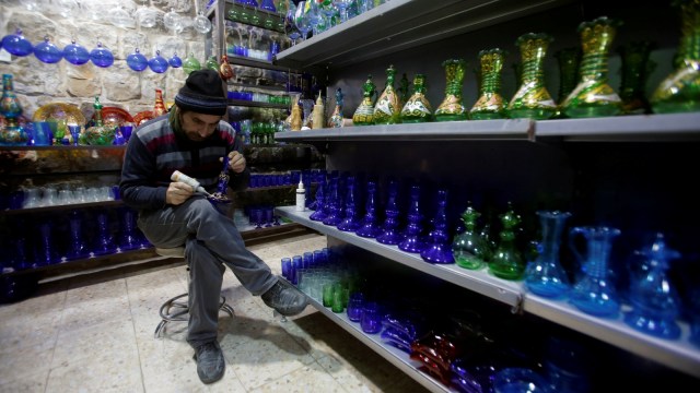 Seorang lelaki Palestina membuat desain untuk pembuatan kaca khas Hebron di Tepi Barat. (Foto: REUTERS/Mussa Qawasma)