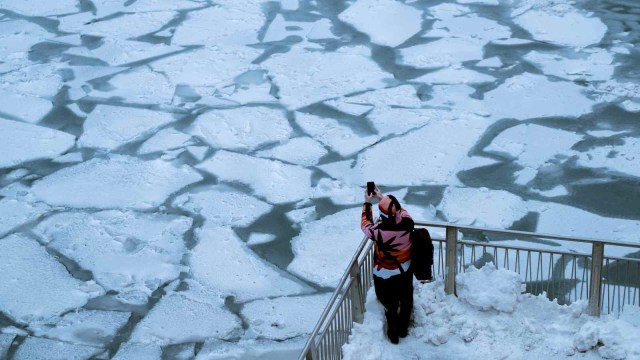Seorang warga mengambil gambar sungai Chicago yang membeku akibat pusaran kutub atau polar vortex (29/1/2019). (Foto: REUTERS/Pinar Istek)