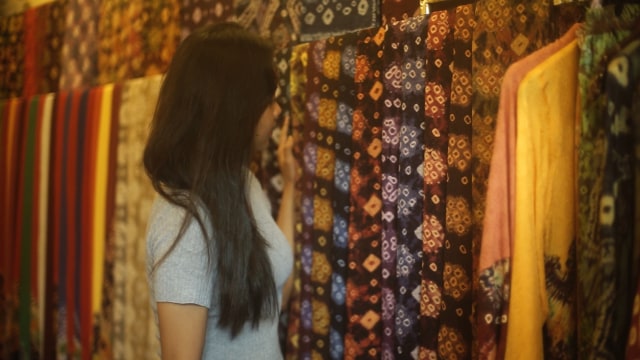 Seorang wanita yang tengah memilih kain jumputan titik tujuh di Galeri Jumputan Tiga Bahar (foto: ABP/Urban Id) 