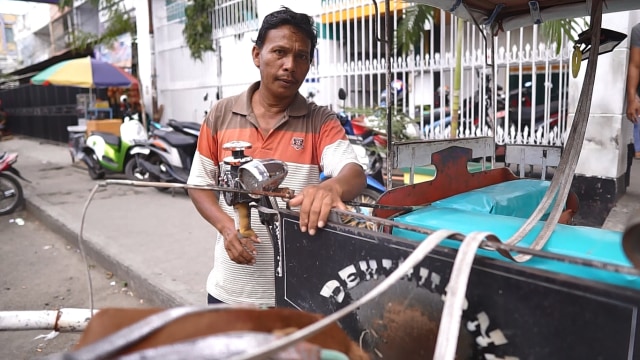 Rusli Lakuo bersama bendinya di depan sebuah pertokoan di Kota Gorontalo, Minggu (17/2). Foto : Tomy Pramono