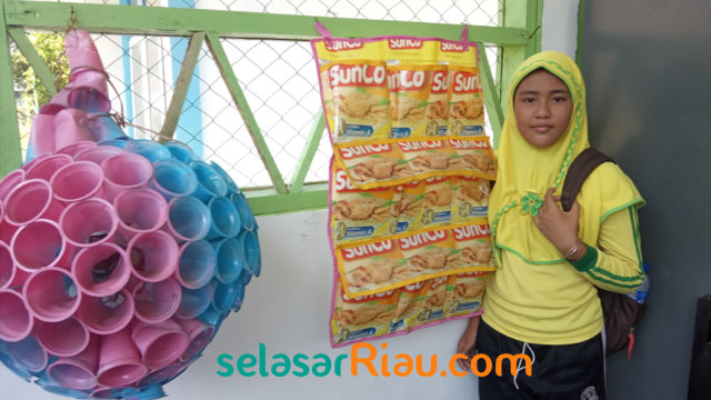SEORANG pelajar berfoto dengan limbah plastik yang disulap jadi kerajinan tangan bernilai tinggi. 