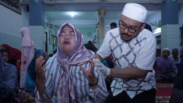 Seorang Ustaz mendampingi peserta rukiah massal di Masjid Miftahussalam. Foto: Fanny Kusumawardhani/kumparan