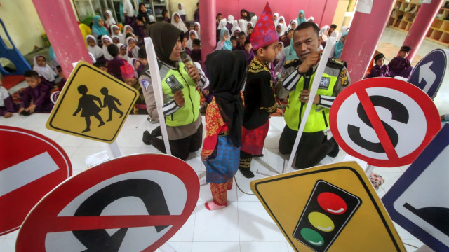 Petugas kepolisian Lalu Lintas Polres Lhokseumawe mengajarkan anak PAUD pemahaman rambu lalu lintas di Taman Kanak (TK) dan PAUD Nurul Iman, Lhokseumawe, Aceh, Kamis (28/2). Foto: ANTARA FOTO/Rahmad