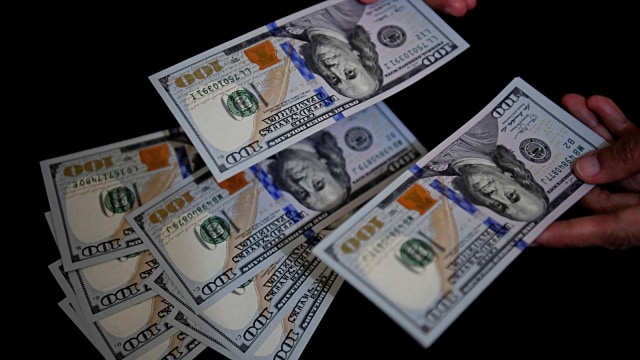 Petugas melayani penukaran uang dolar Amerika di salah satu gerai penukaran valuta asing, Jakarta. Foto: Antara/Puspa Perwitasari