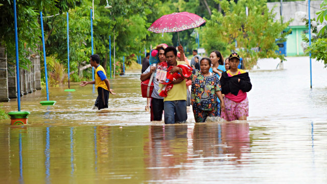 Sejumlah warga berjalan menerobos banjir untuk mengungsi di Desa Garon, Kecamatan Balerejo, Kabupaten Madiun, Jawa Timur Foto: Antara/Siswowidodo