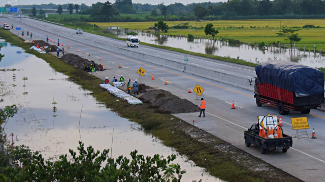 Sejumlah pekerja menguruk tepi jalan tol Trans Jawa ruas Ngawi-Kertosono yang sebelumnya terendam banjir di Desa Glonggong, Balerejo, Kabupaten Madiun. Foto: Antara/Siswowidodo