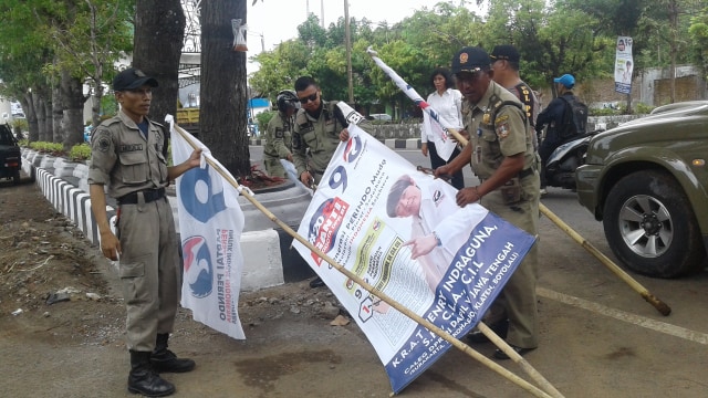 Petugas satpol PP melepas APK yang melanggar aturan pada Minggu (10/03/2019). (Agung Santoso)