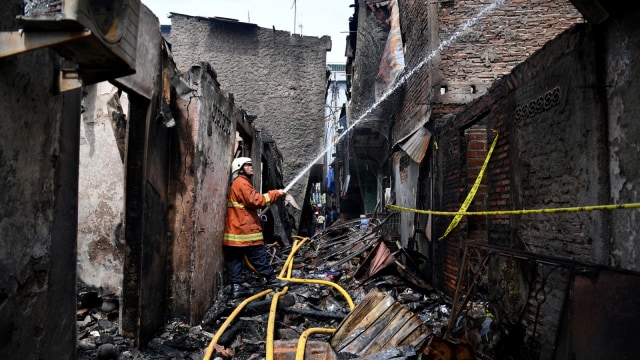Petugas pemadam kebakaran mendinginkan sisa kebakaran yang melanda permukiman padat di kawasan Krukut, Tamansari, Jakarta Barat, Minggu (17/3). Foto: ANTARA FOTO/Sigid Kurniawan