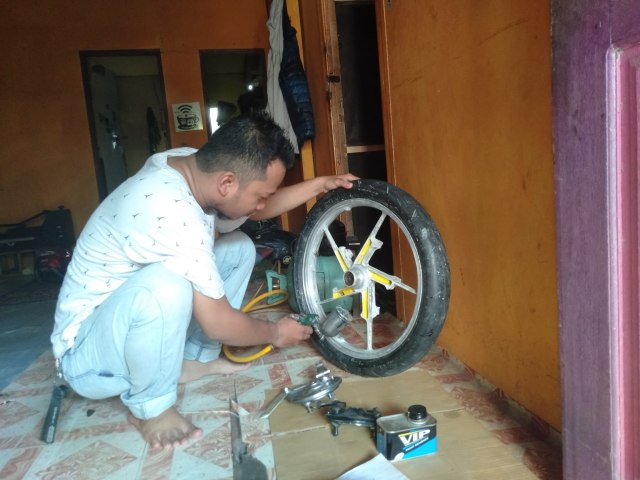 Aditya Prayuda, lulusan Sarjana Pendidikan jebolan Universitas Lambung Mangkurat sibu mengecat aneka sparepart, Senin (18/3). Foto: Zahidi/banjarhits.id