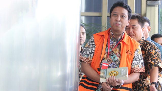 Anggota DPR Fraksi PPP Nonaktif Romahurmuziy menutupi borgol dengan buku saat tiba di Gedung KPK. Foto: ANTARA FOTO/Reno Esnir