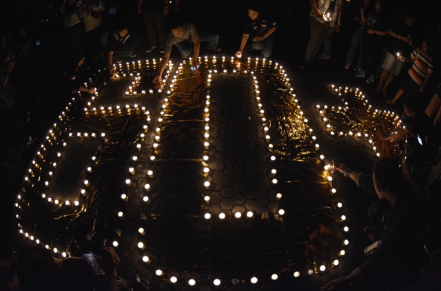 Warga menyalakan lilin membentuk angka 60 plus saat peringatan Earth Hour di Tugu Mandala, Nusa Dua Bali, Sabtu (30/3/2019). Foto: ANTARA FOTO/Fikri Yusuf