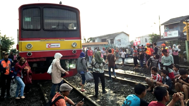 Warga melintasi perlintasan di sekitar Stasiun Sudimara yang terganggu akibat KRL mogok. Foto: Reza Aditya/kumparan