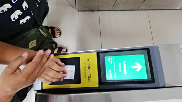 Petugas membantu penumpang saat menempelkan kartu tiket MRT. Foto: Darin Atiandina/kumparan