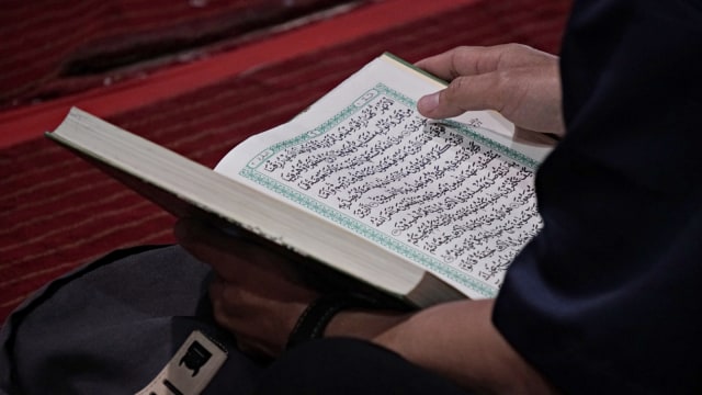 Seorang pria sedang membaca ayat suci Alquran. Foto: Iqbal Firdaus/kumparan