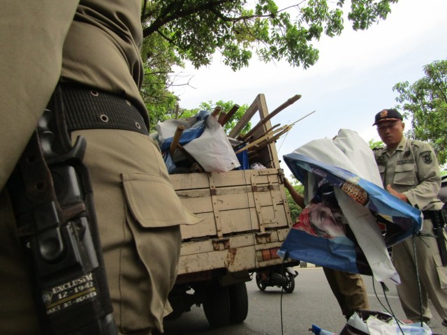 Personel Satpol PP menertibkan Alat Peraga Kampanye peserta Pemilu 2019 di seputaran Kota Banda Aceh, Minggu (14/4). Foto: Jufrizal untuk Acehkini