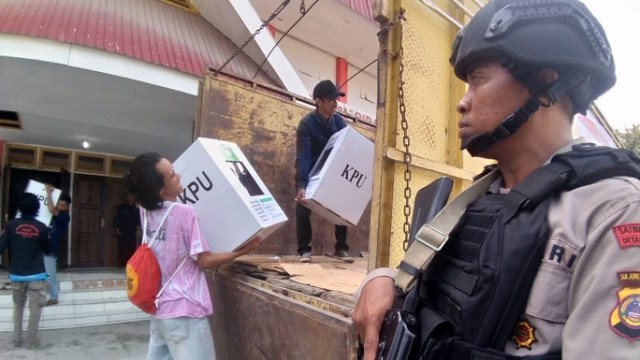Salah satu petugas kepolisian saat menjaga ketat penyaluran logistik di salah satu lokasi PPK di Kota Palu, Senin (15/4). Foto: Jems