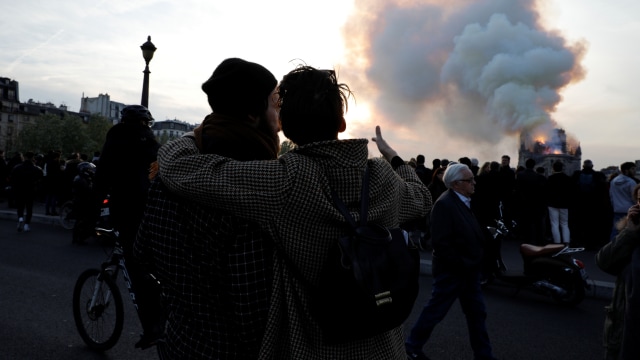 Warga menyaksikan asap dan kobaran api selama terjadinya kebakaran di Katedral Notre Dame,  Paris, Prancis. Foto: AFP