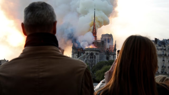 Warga menyaksikan asap dan kobaran api selama terjadinya kebakaran di Katedral Notre Dame,  Paris, Prancis. Foto: AFP