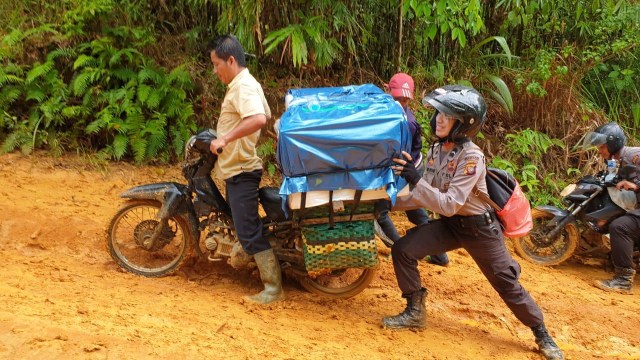 Akiau bersama rekannya dan warga mendorong kendaraan yang mengangkut logistik surat suara pemilu 2019. Foto: Dok Hi!Pontianak